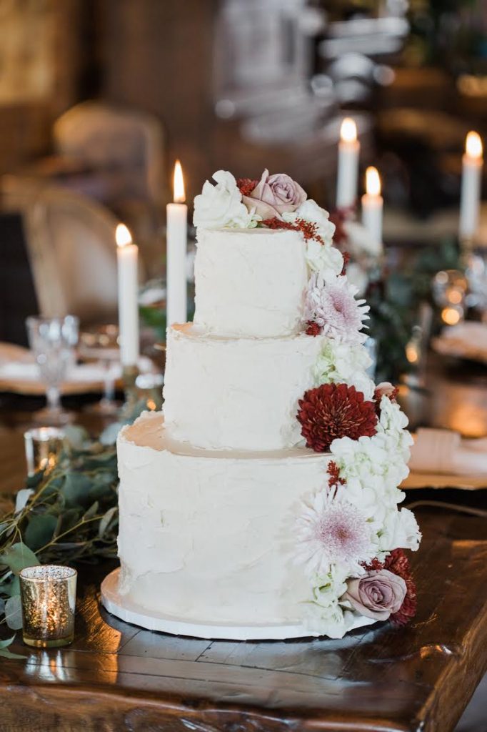 3-tier white wedding cake with real white, pink, and red flowers