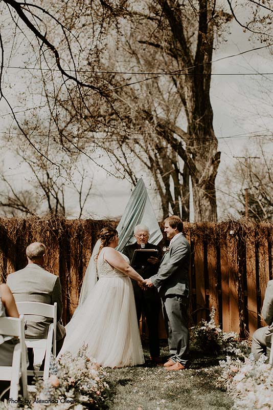 Bride and groom exchanging vows at a backyard wedding