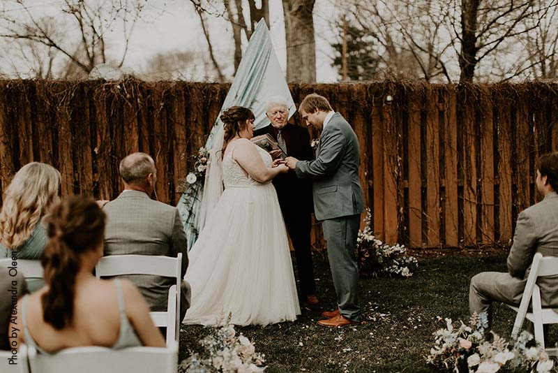 Groom giving the bride her ring at the backyard wedding