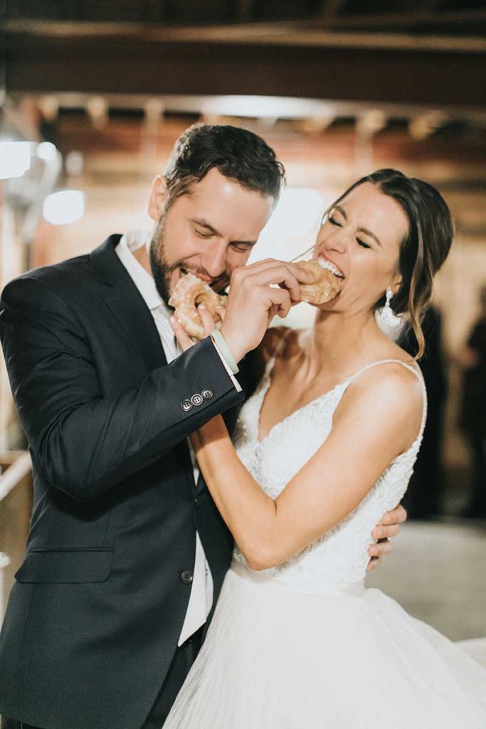 Bride and groom feed each other donuts at wedding