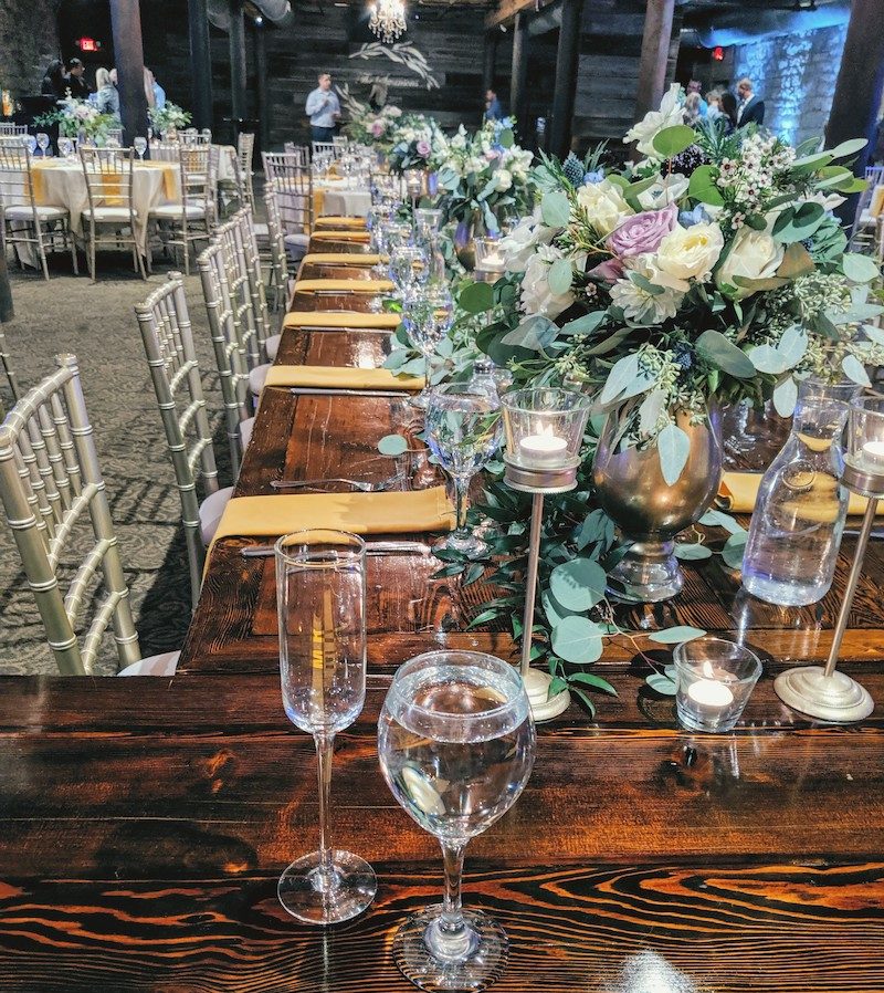 Eucalyptus bouquets and glassware on wooden wedding tabletop