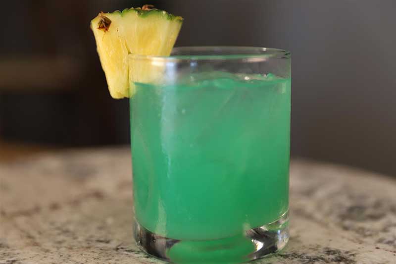 Blue rum cocktail garnished with pineapple