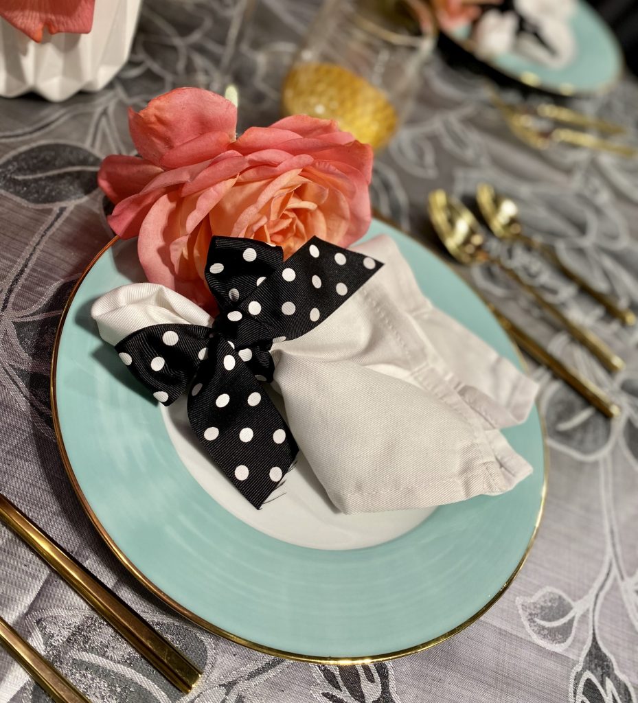 Blue wedding plate with polka dot napkin and pink flower