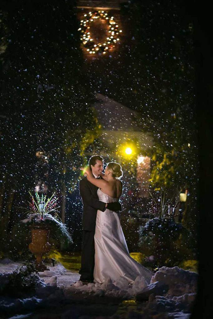 Bride and groom stand as snow falls during unpredictable weather