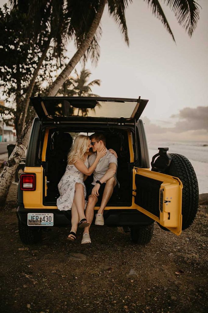 Couple sits in yellow jeep on mountain