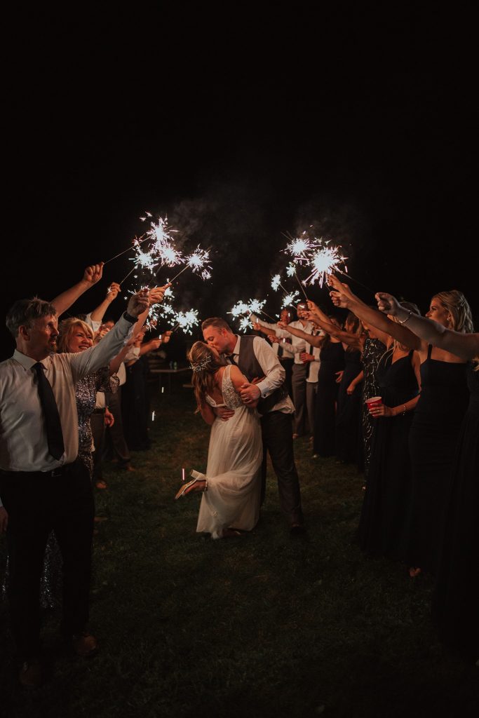 Bride and groom kiss under sparklers
