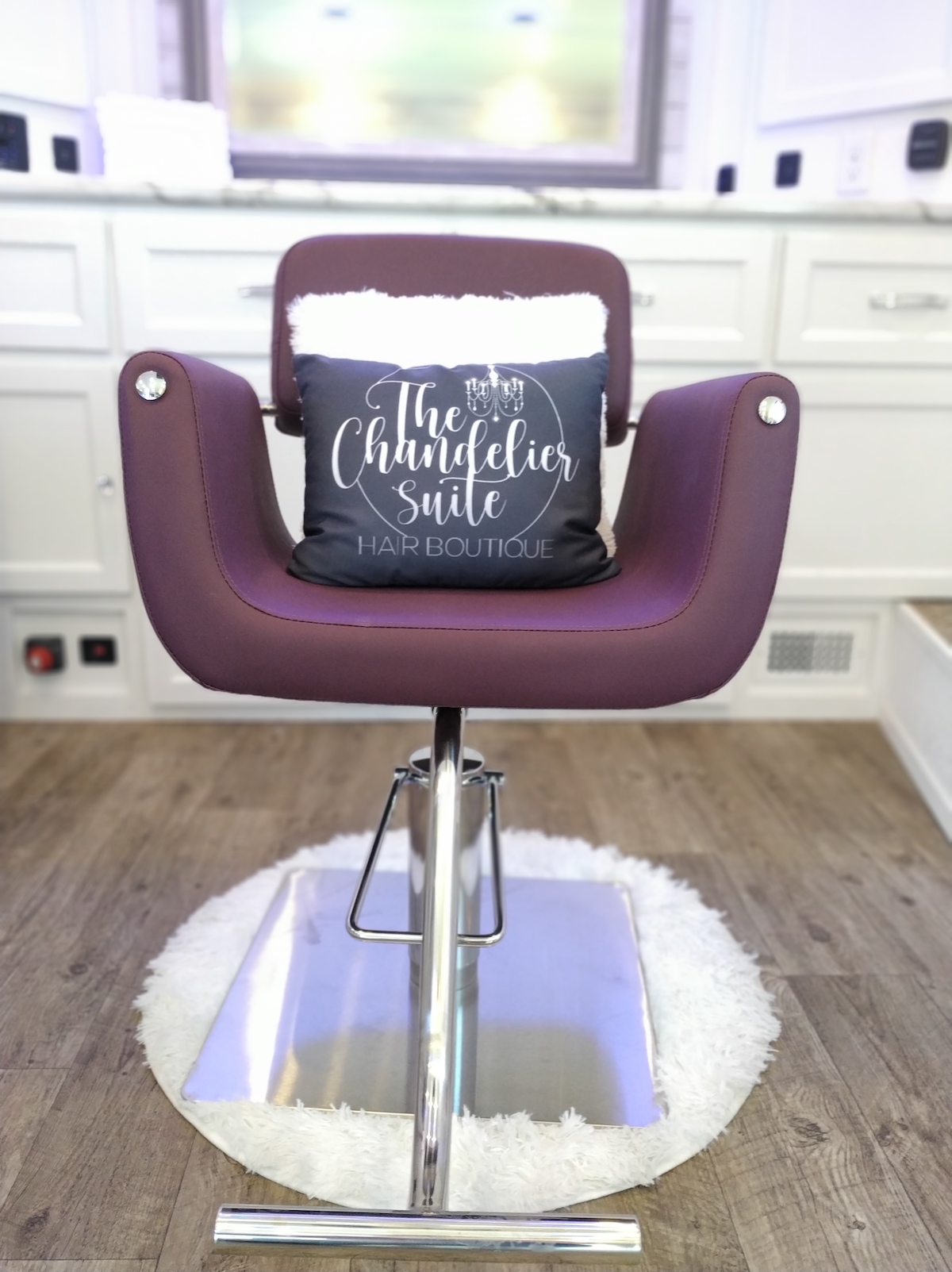 Purple beauty chair with pillow that says "The Chandelier Suite"