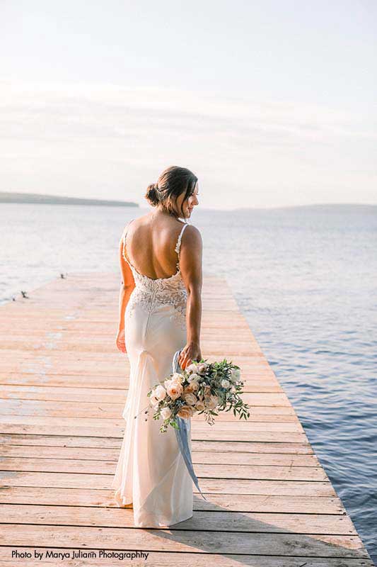 Bride stands on dock by lake
