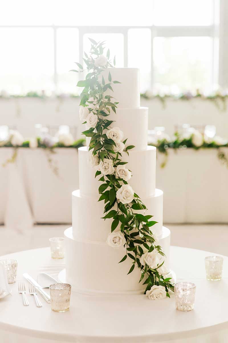 5-tier white wedding cake with live greenery and roses