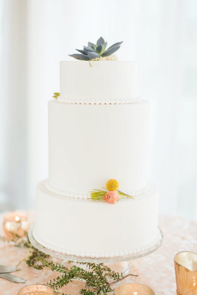 3-tier white wedding cake with succulent on top and beading between layers