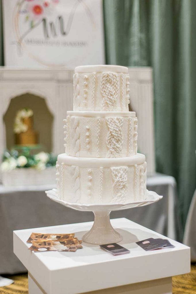 3-tier white wedding cake with piping resembling a sweater