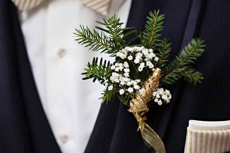 Winter boutonnière with gold wrap, baby's breath, and pine 