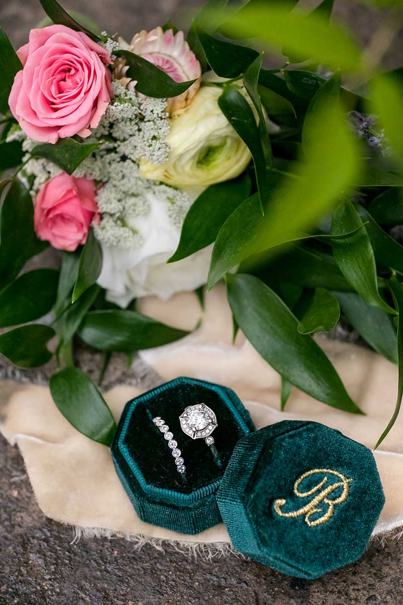 Wedding engagement ring and band sit inside a velvet green box