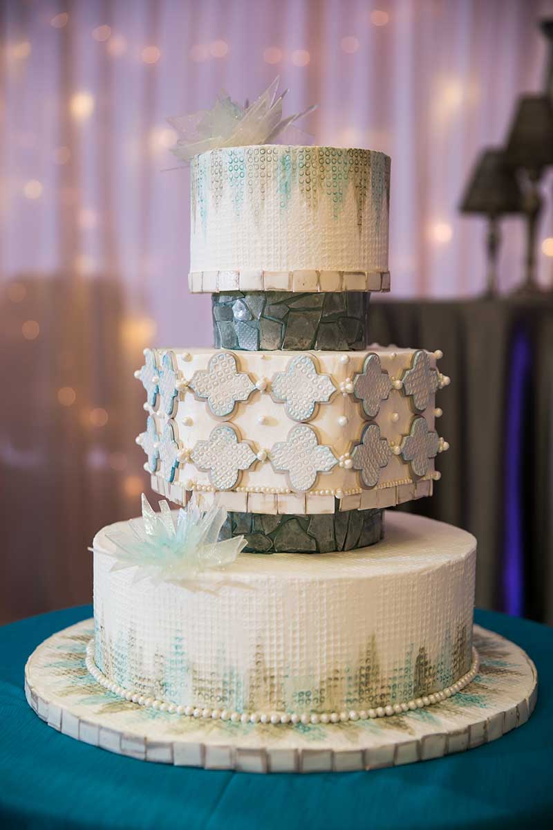 3 tier white wedding cake with gold and blue detailing