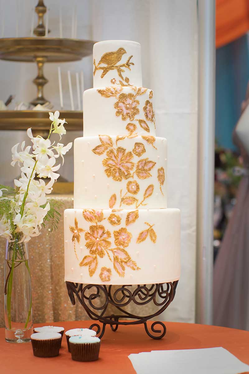 4-tier white wedding cake with gold painted flowers 