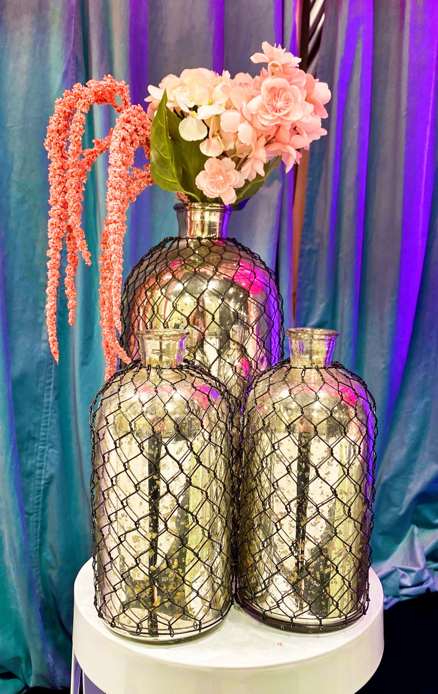 Tall gold vases in black cages with pink and blue flowers 