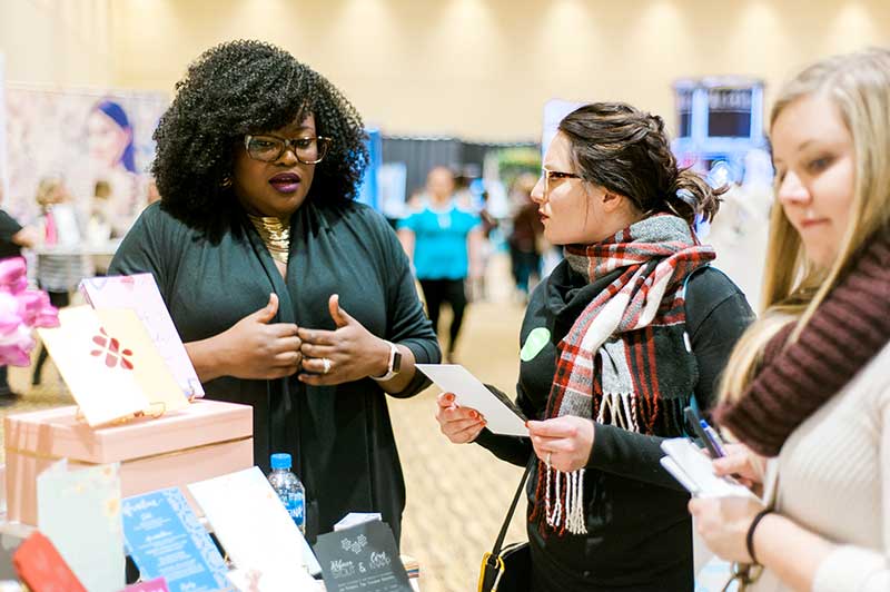 Bridal show vendor talks to bride at Unveiled Rochester 2021