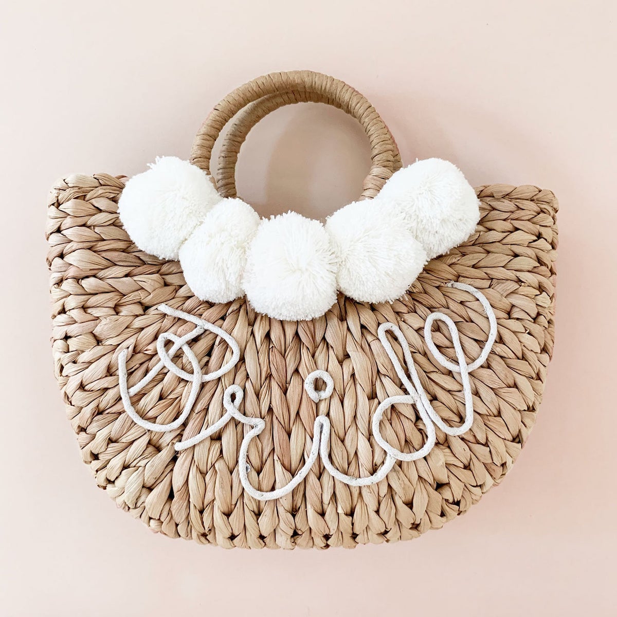 Woven bag that says "Bride" with white pom balls 