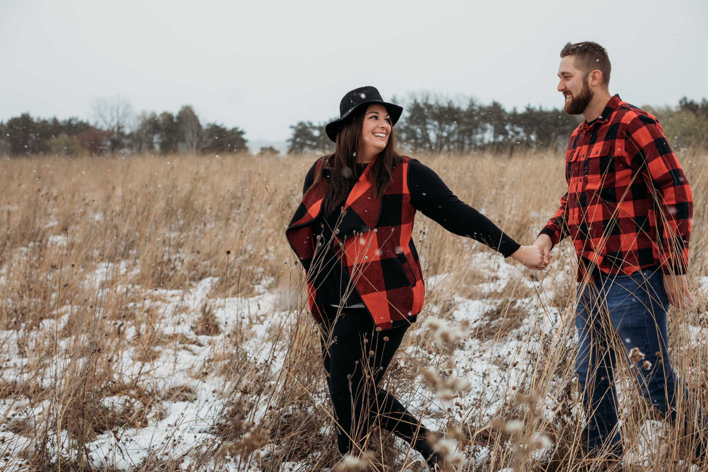 Couple walks through field in engagement photo by a woman-owned wedding business