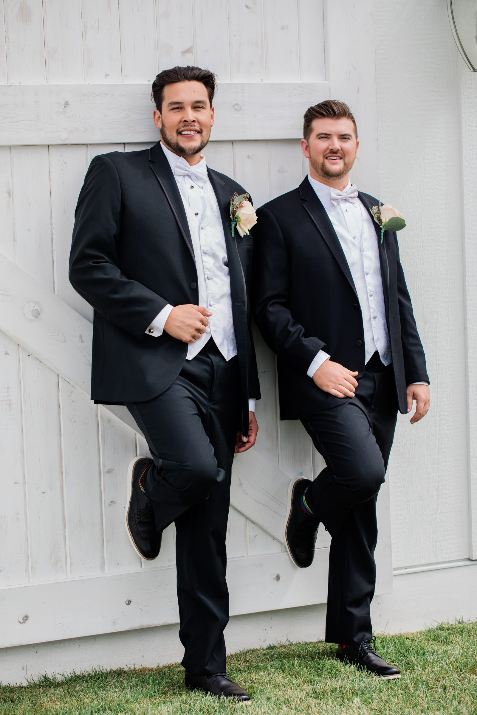 Grooms stand in front of barn at Minnesota wedding