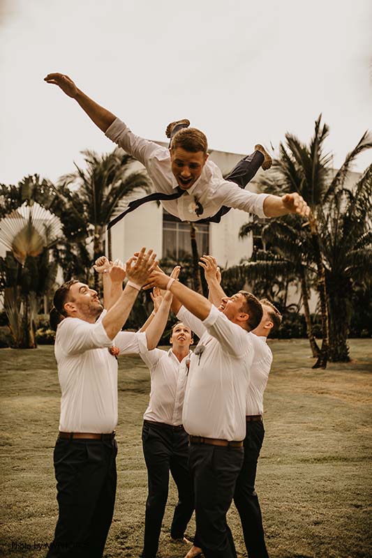 Groomsmen toss groom in the air