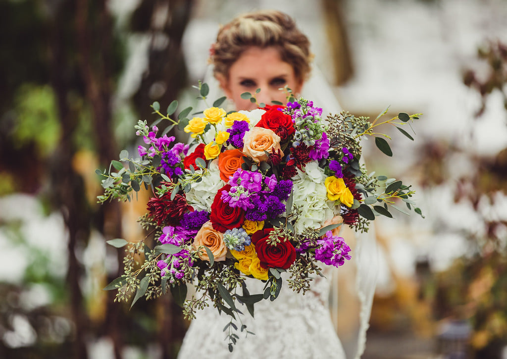 Bright bouquet with colored roses, purples, peaches, red and greenery