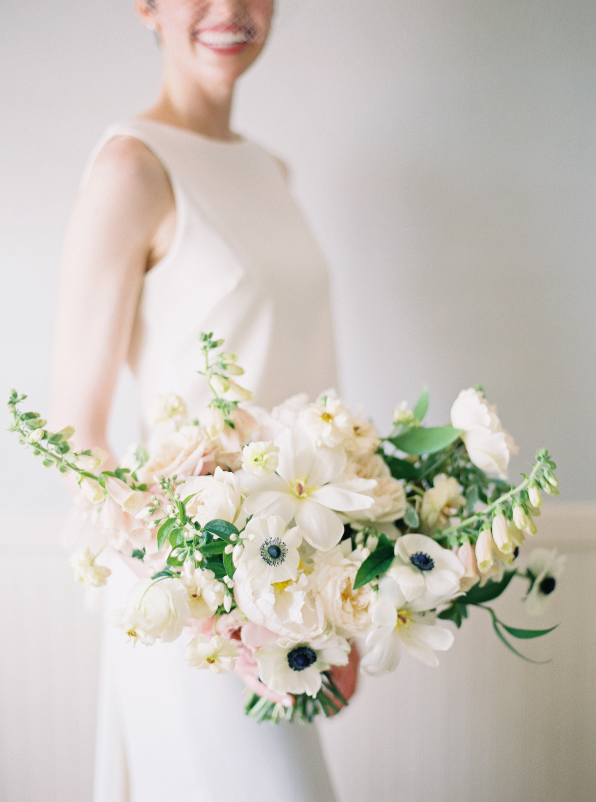 White spring bridal bouquets with tulips, anemones, peonies, roses, and ranunculus 