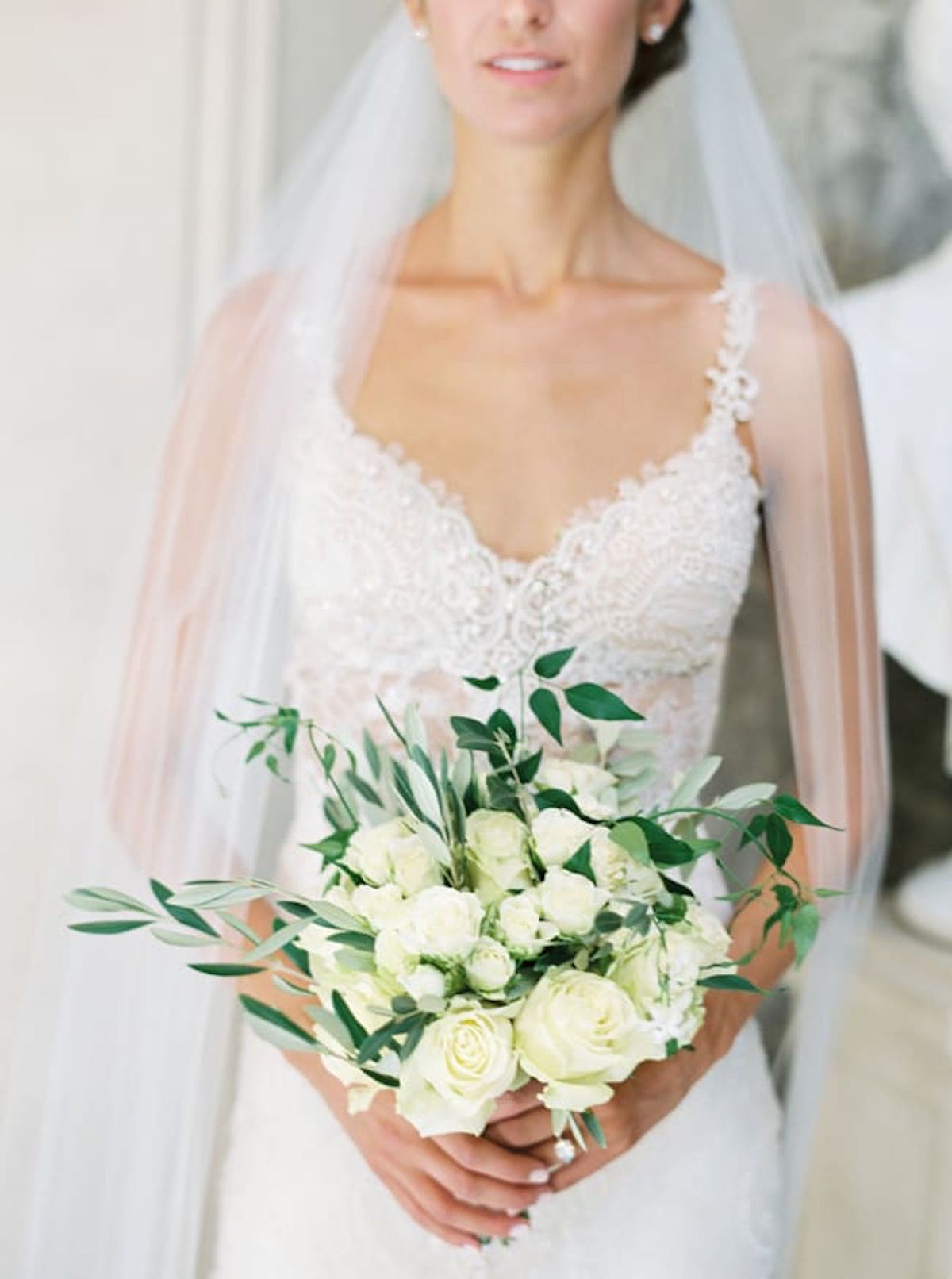 Bride poses with white rose bridal bouquet 