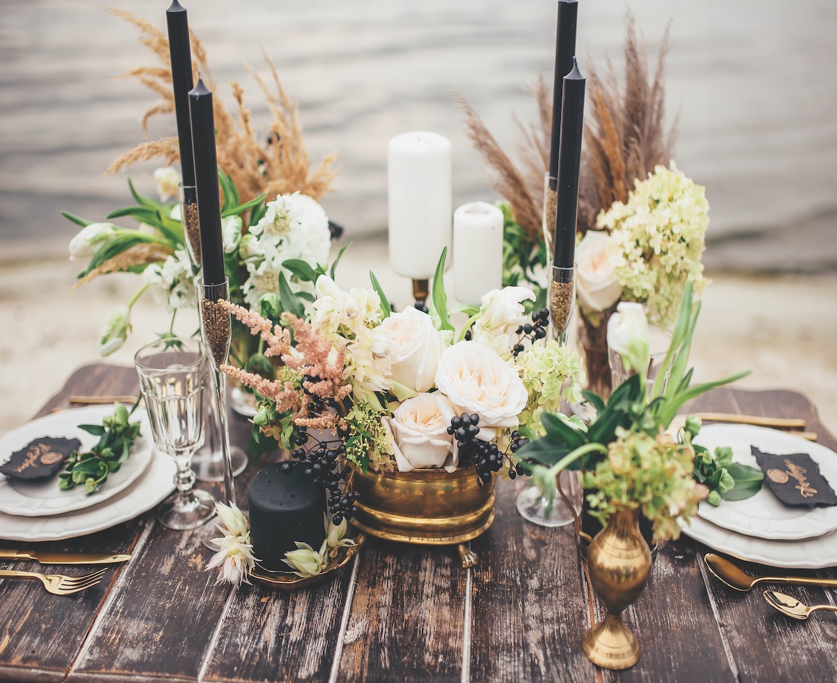 Modern rustic wedding decor with gold candle holders and black taper candles on a wooden table for two