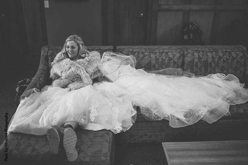 Bride sits on couch with dress laid out