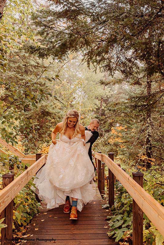 Bride in boots walks along bridge in the forest