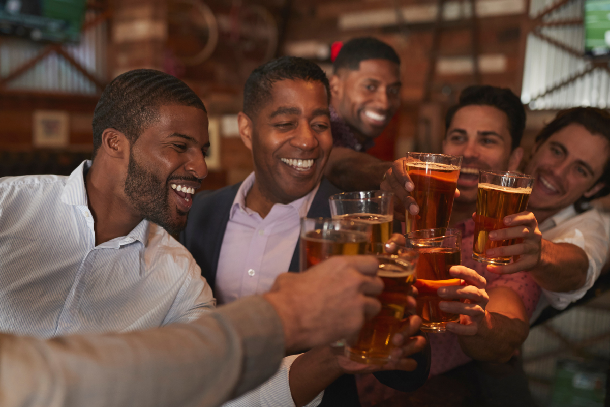 Men having a sophisticated bachelor party at a brewing while cheers-ing beers