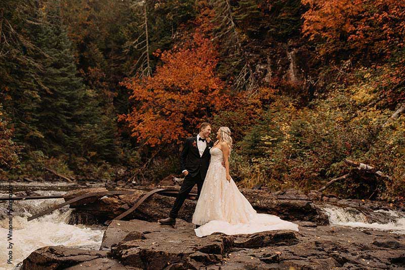 Bride and groom stand on rocks at fall wedding in Minnesota
