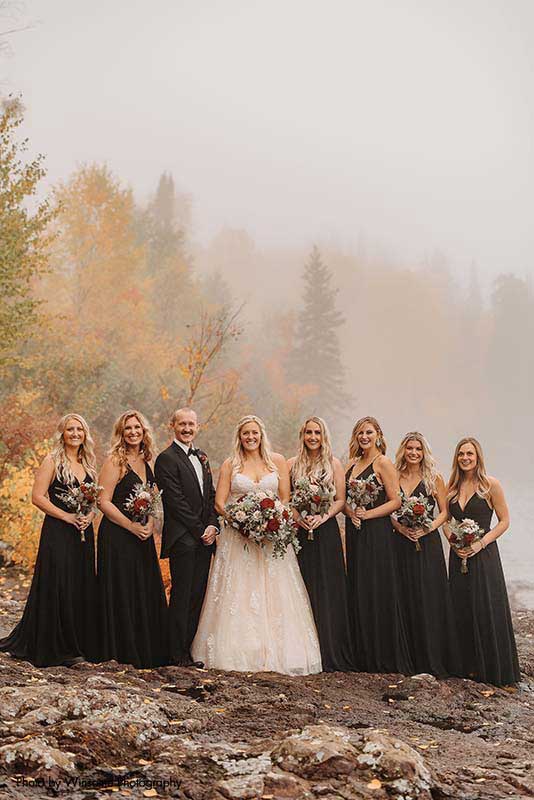 Bride stands with bridesmaids and man on honor in black dresses and suit