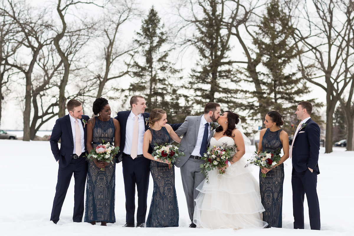 Bridal party stands outside in snow for winter wedding