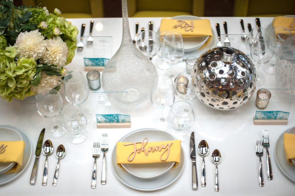 Modern and bright wedding tablescape with yellow napkins and chrome silverware and vases
