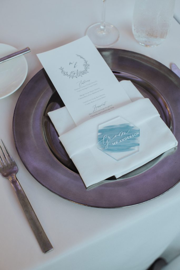 Summer wedding colors tabletop with purple charger and acrylic blue place cards