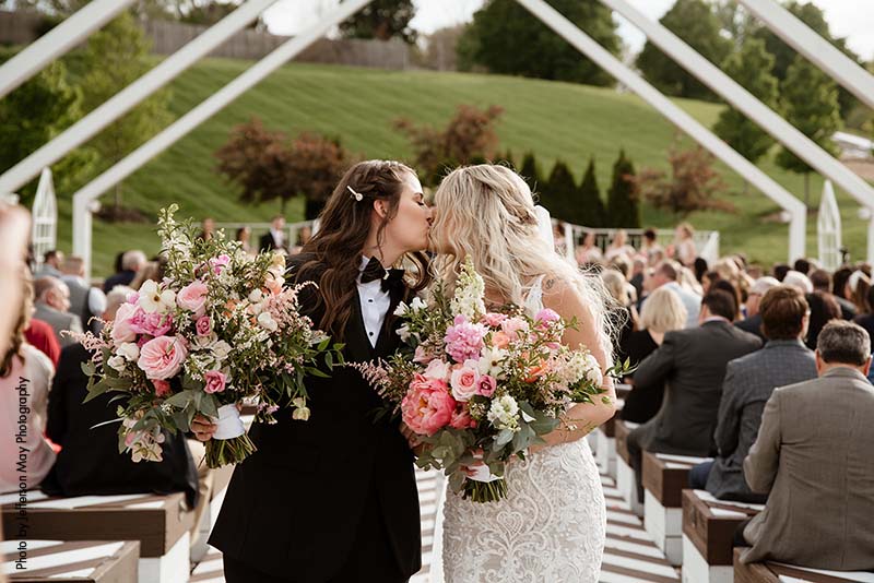 Brides kiss as they walk down aisle after ceremony
