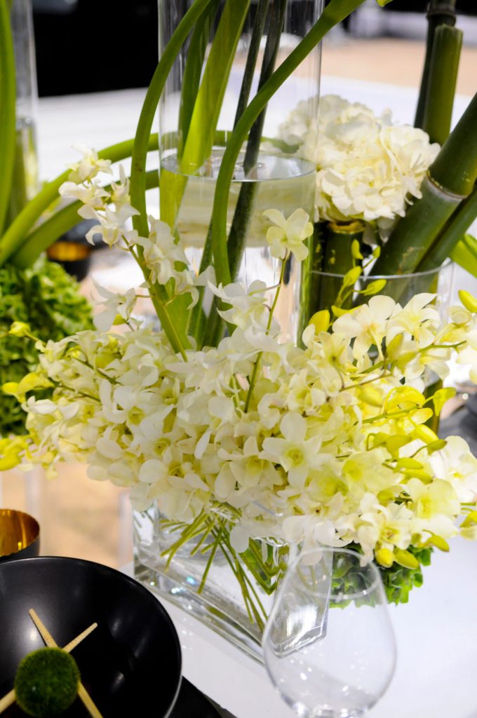 Calla lillies and greens sit in clear vase at wedding table