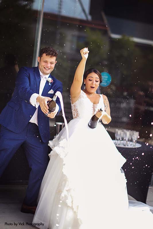 Bride and groom popping champagne after micro wedding