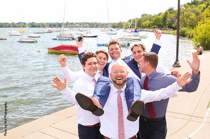 Groomsmen holding up groom on dock