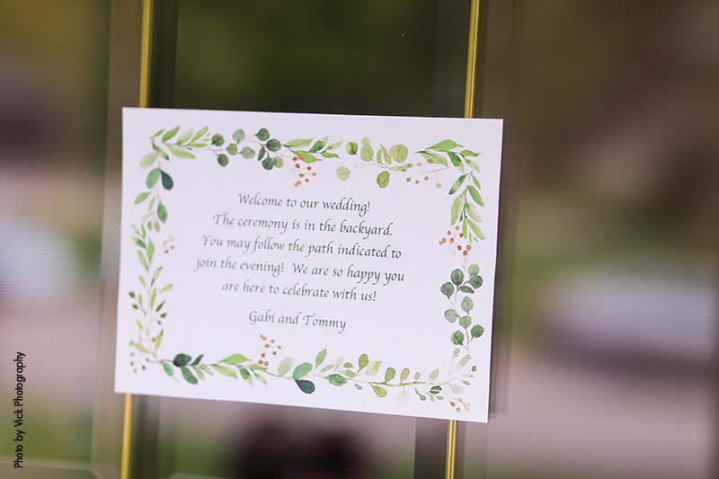 White wedding welcome sign with green floral detail