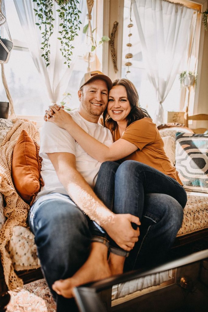 Couple sits on couch for Minneapolis at-home engagement photoshoot by Winsome Photography 