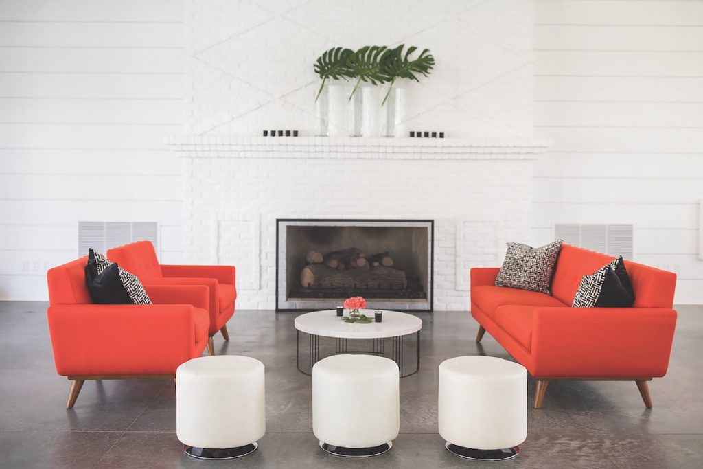 Coral mid-century sofas with white ottomans as wedding lounge space 