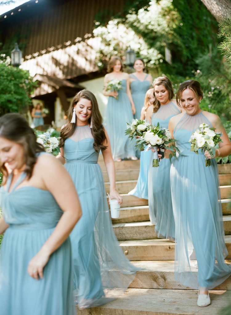 Bridesmaids wearing full length blue gowns by Bella Bridesmaids for outdoor country wedding. Florals by Jackson Durham.