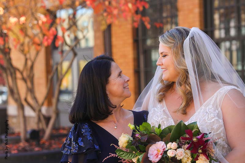 Bride in veil looks at mother of the bride in navy gown
