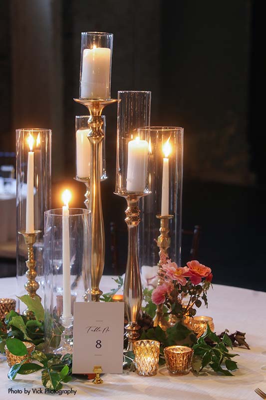 Wedding table with several taper candles and greenery
