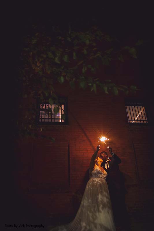 Bride and groom light a sparkler outside after wedding