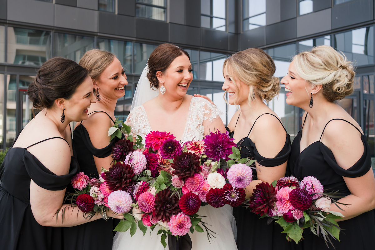 Jewel-toned wedding flowers held by bride and bridesmaids in black dresses